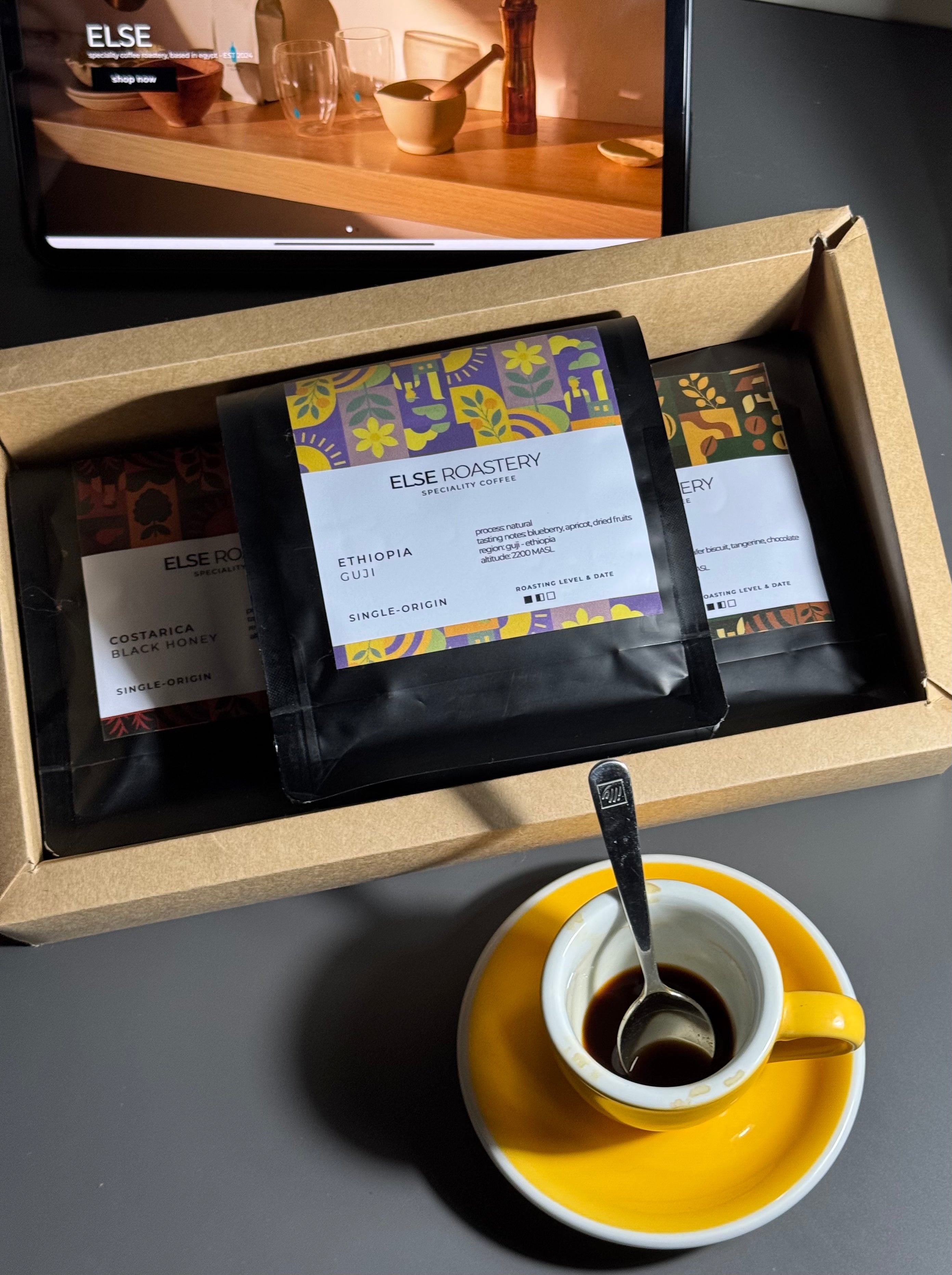 Coffee packaging with coffee beans and a cup of coffee on a dark surface
